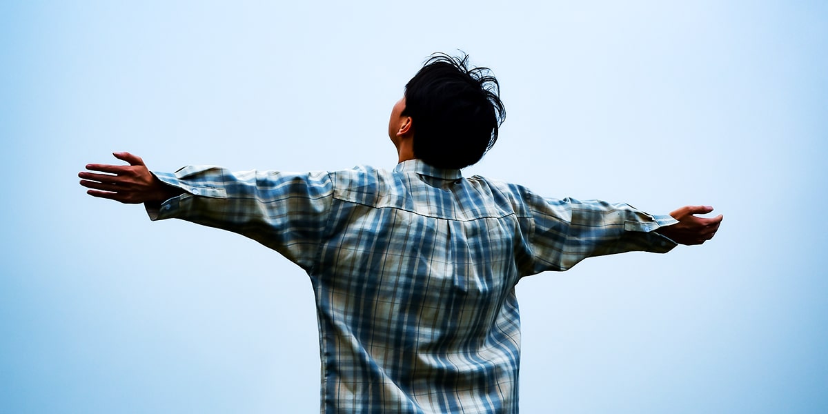 man lifting his arms and head and talking to the sky