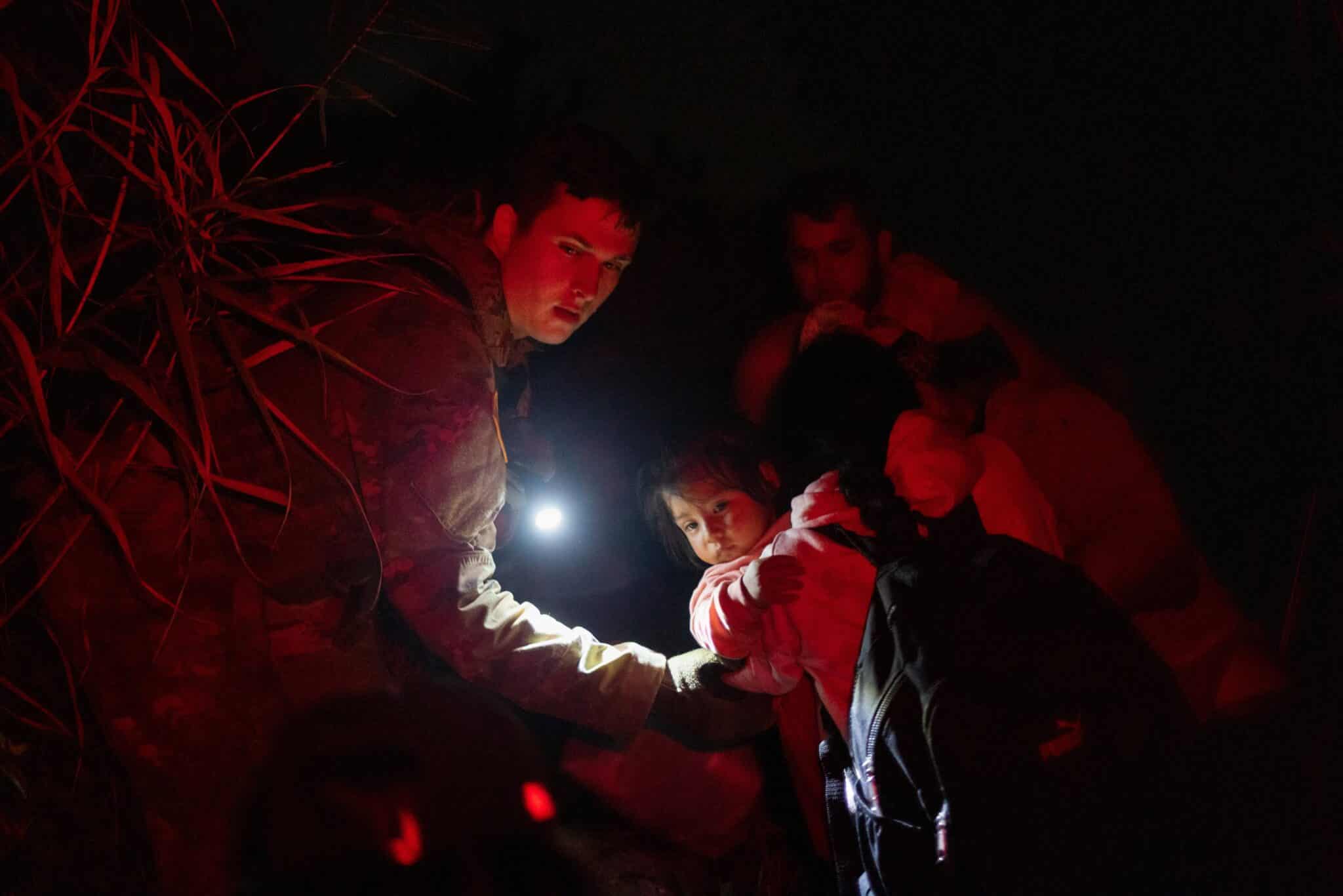 A member of the Texas Army National Guard assists migrants, including Amaiia, a then-1-year-old asylum seeker from Nicaragua, as she and her mother Angelita navigate trails in the dark after crossing the Rio Grande into Roma, Texas, May 8, 2022. Many Nicaraguans continue fleeing their country because of political instability. (OSV News photo/Adrees Latif, Reuters)